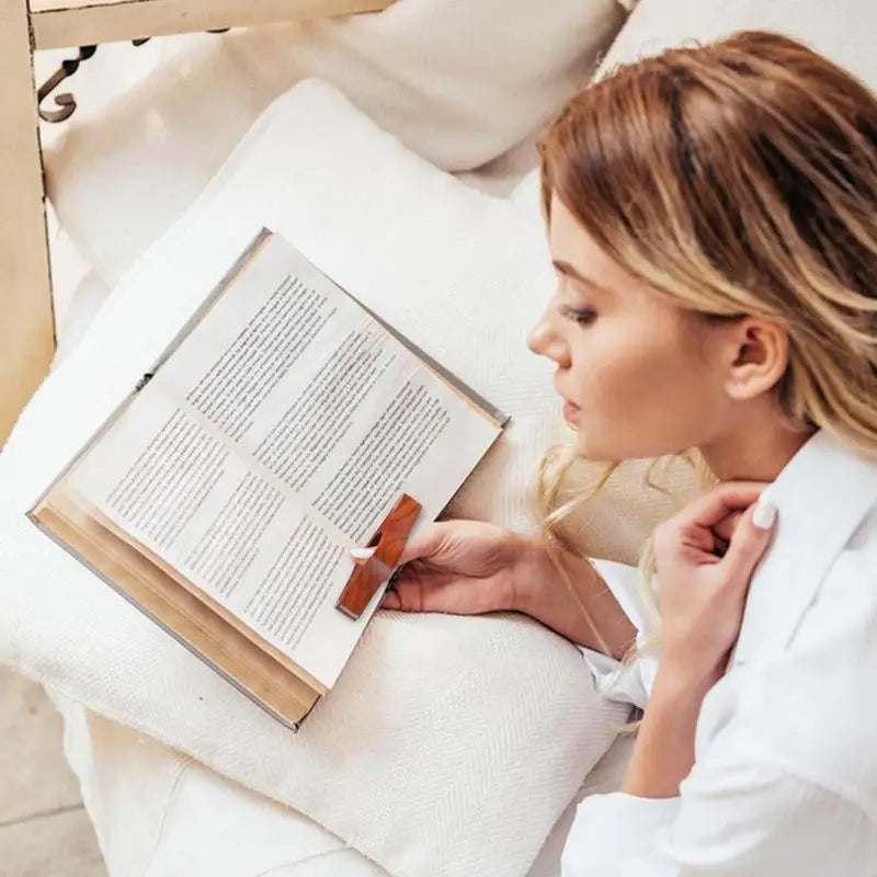Woman reading a book in bed using a wooden thumb page holder